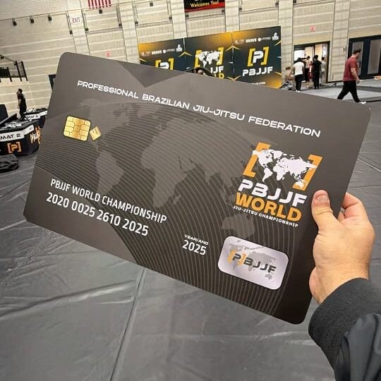 Cheque simbólico do Mundial da PBJJF exposto na arena de 2025; para 2026, a federação promete mais de US$ 70 mil em prêmios.